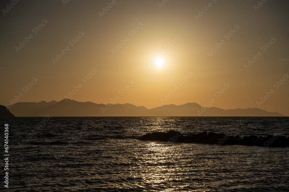 View of sea and island silhouette at sunset golden hour.