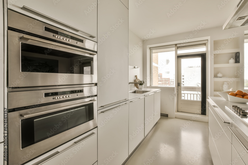 a kitchen with two ovens and an open door leading to the outside space in front of the counter area a kitchen with two ovens and an open door leading to the outside space in front of the counter area