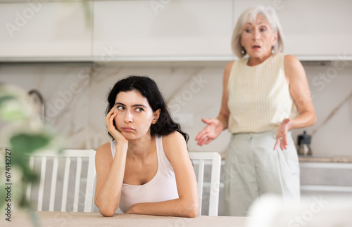 Aggrieved elderly woman having quarrel with her daughter at home. Elderly mother expresses claims to adult daughter