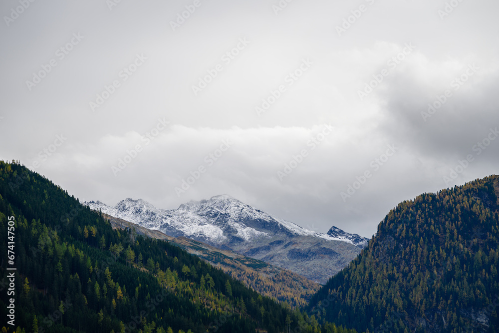 landscape with clouds over snowcapped peaks in the alps in autumn
