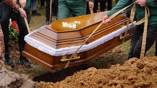 Burial. Men lower the coffin into the grave.