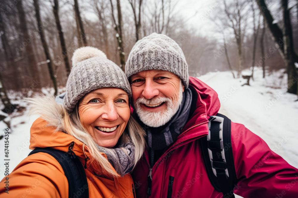 portrait of happy senior couple taking selfie photo while enjoying hike in winter forest