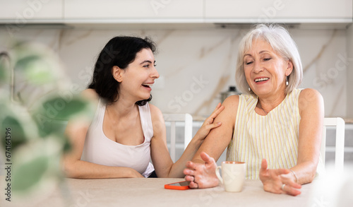 Family tea party - an elderly mother and an adult daughter drink tea together and talk cheerfully