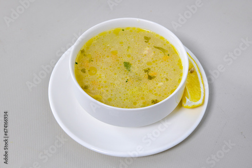 Homemade turkish soup Tavuk Suyu corbasi in a white ceramic soup plate.Turkish noodle chicken broth soup on a plate. Turkish meal (sehriyeli tavuk suyu corbasi)