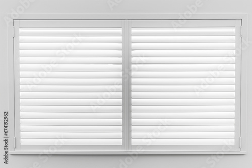 Window with white shutters on a white wall