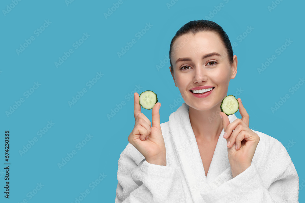 Beautiful woman with pieces of cucumber on light blue background, space for text Beautiful woman with pieces of cucumber on light blue background, space for text