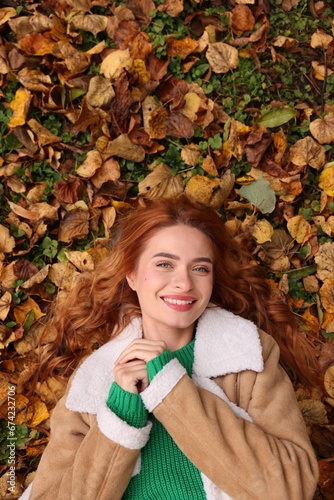 Smiling woman lying among autumn leaves outdoors  top view