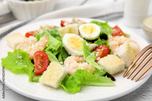 Delicious Caesar salad with shrimps and fork served on table, closeup