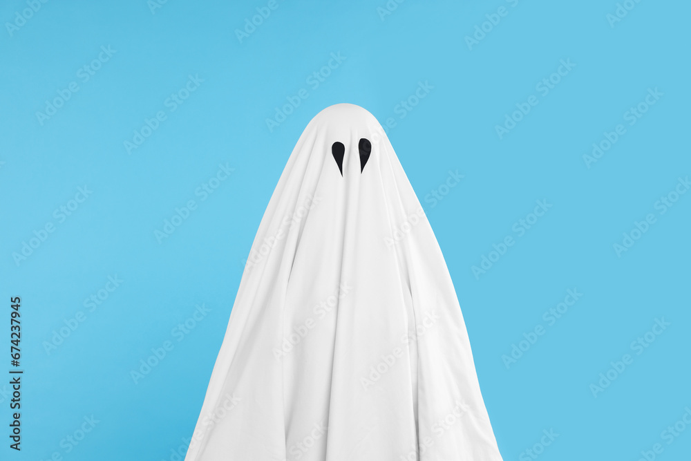 Woman in white ghost costume on light blue background. Halloween celebration Woman in white ghost costume on light blue background. Halloween celebration