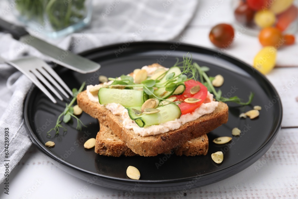 Tasty vegan sandwich with cucumber, tomato and pumpkin seeds on white wooden table, closeup Tasty vegan sandwich with cucumber, tomato and pumpkin seeds on white wooden table, closeup