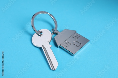 Key with keychain in shape of house on light blue background, closeup © New Africa