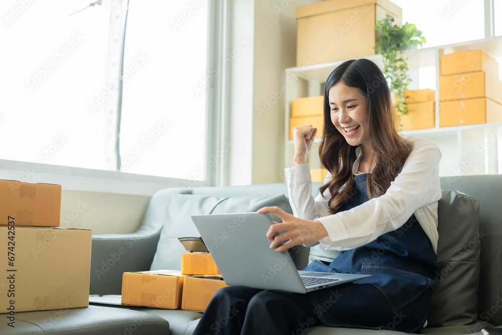 Happy Asian woman receives good news from online name order, SME parcel box and uses smartphone to order online email in SME seller chat box, concept Happy Asian woman receives good news from online name order, SME parcel box and uses smartphone to order online email in SME seller chat box, concept