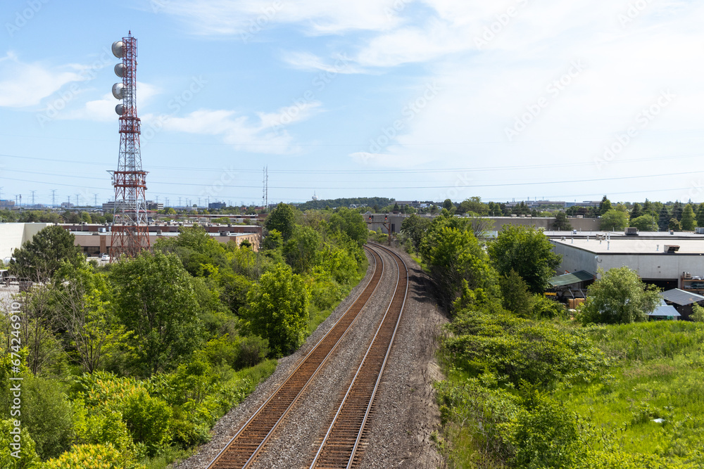 Railroad tracks - greenery - industrial area - tower - blue sky