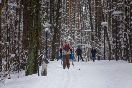 People are walking on cross-country skis in a snow-covered city park © Дворецкая Таня