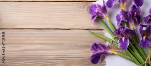 Three vibrant irises placed on a wooden surface accompanied by a present resting on a crisp white napkin