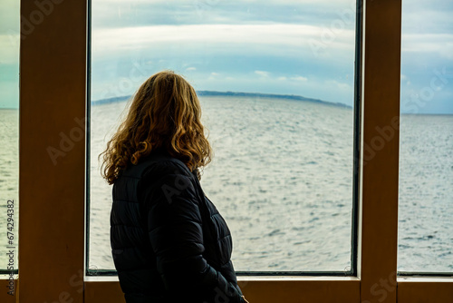 Helsingborg, Sweden A woman looks out a window of a ferry  whose view is distorted on a ferry to Denmark. © Alexander