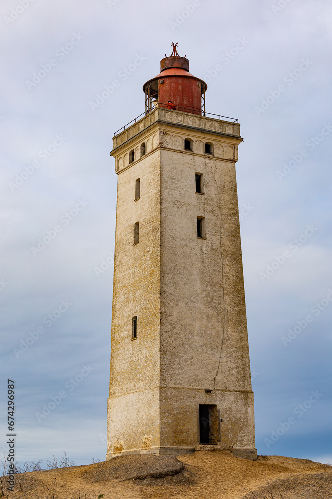 Rubjerg Knude Lighthouse, Denmark A view of the famous Rubjerg Knude lighthouse that was moved due to dune and water erosion in 2018, and people walking.