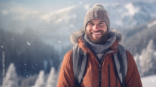 Portrait of a young handsome smiling man in a jacket against the backdrop of a winter snowy landscape.