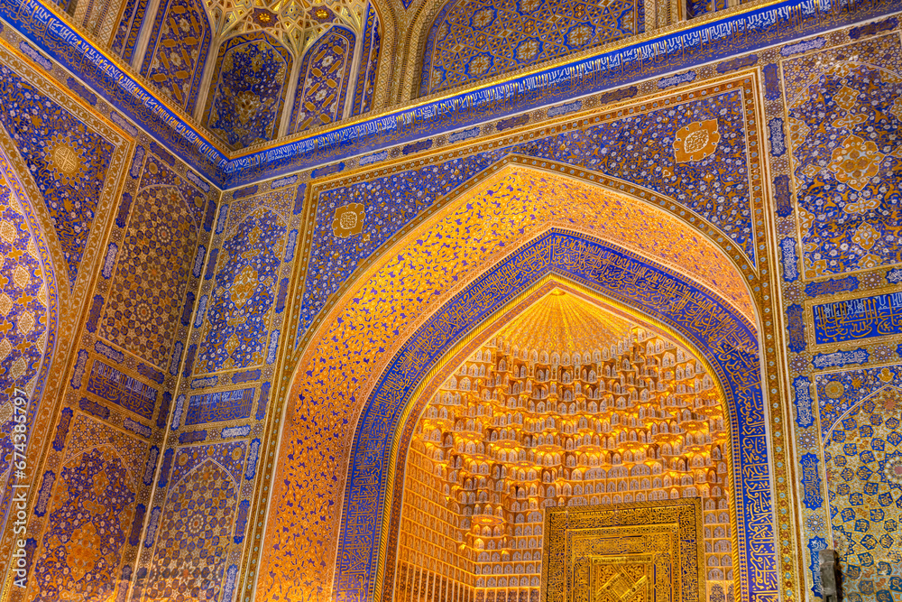 Interior of Tilya Kori Madrasah in Samarkand, Uzbekistan. Masterpiece of XVII cent. Mihrab upper part, golden and blue ornaments. Arabic text of Qran (sacred book of muslims) used as part of ornament
