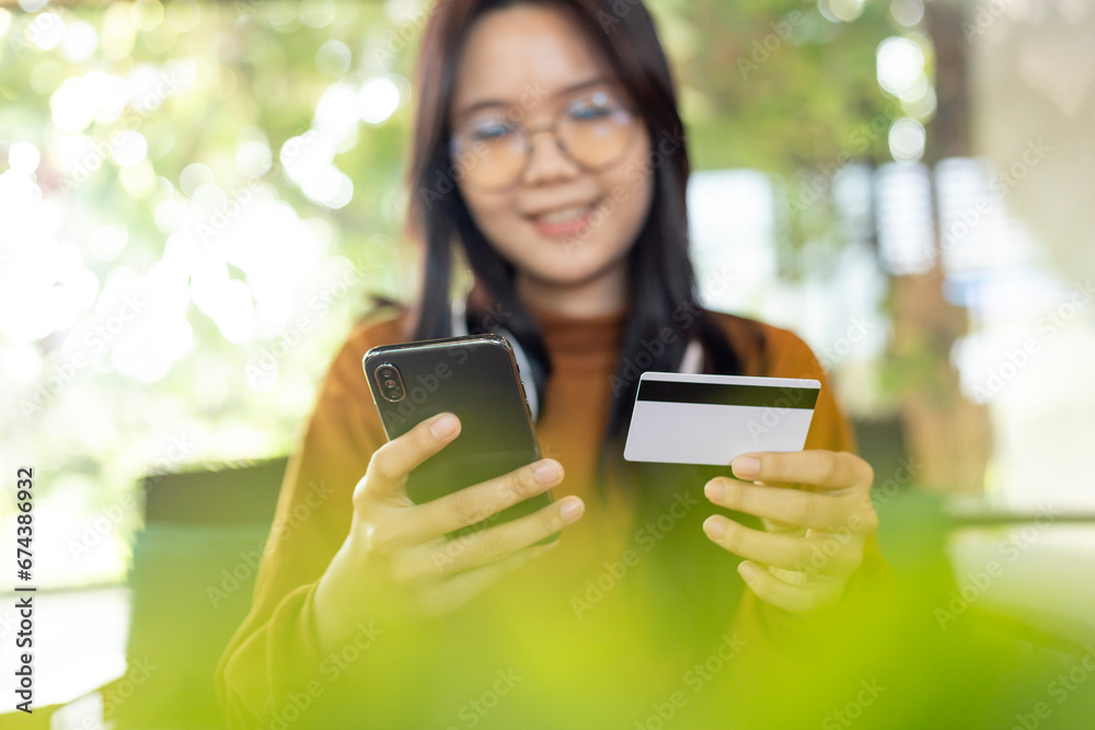 Asian woman holding smartphone and credit card to shopping online and paying her order Asian woman holding smartphone and credit card to shopping online and paying her order