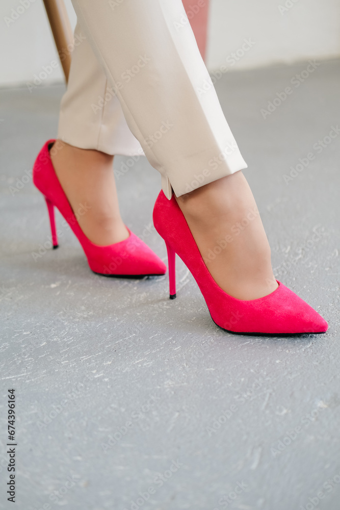Pink high-heeled shoes. Women's legs close-up. A woman in flesh-colored clothes and pink high-heeled shoes.