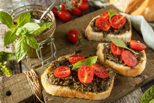 Homemade bruschetta with pesto sauce, fresh tomatoes on a wood background. Traditional italian appetizer or snack, antipasto.