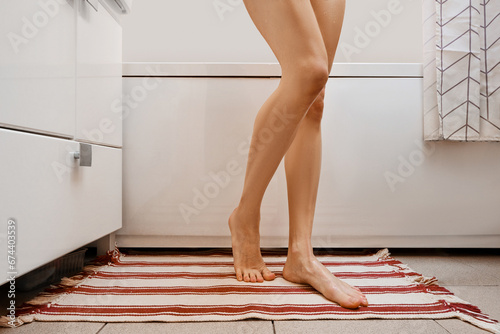 Unrecognizable woman came out of bath and is standing on mat