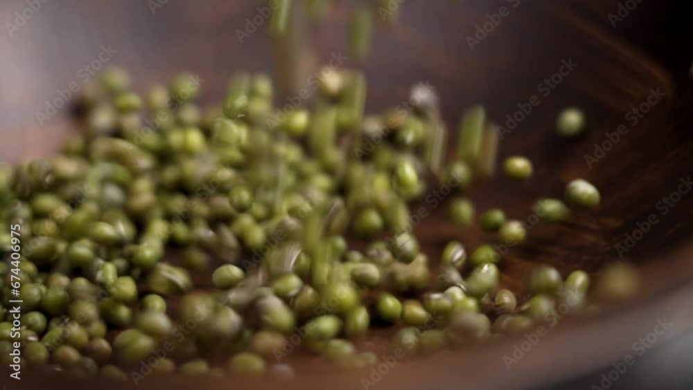 Dried mung beans falling into a dark wooden bowl for healthy dietary garnish cooking close up. Rotation Dried mung beans falling into a dark wooden bowl for healthy dietary garnish cooking close up. Rotation