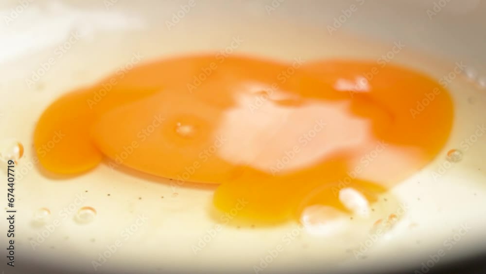 Falling broken egg on a frying pan close up in slow motion. Macro shot Falling broken egg on a frying pan close up in slow motion. Macro shot