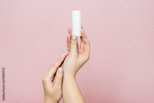 Hand holding white bottle. Drops for eye, nose or ear in hand on pink background. Pharmaceutical product.