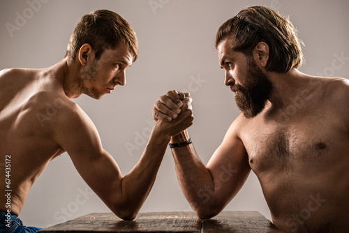 Two man's hands clasped arm wrestling, strong and weak, unequal match. Arm wrestling. Arms wrestling thin hand, big strong arm in studio