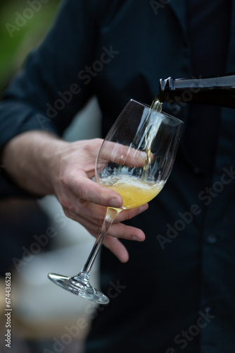 The waiter pours cider into a glass