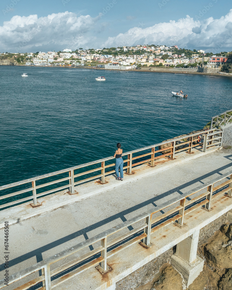 Aerial view of a woman walking on Vivara bridge connecting Vivara Island Natural reserve and Procida Island, Flegree Islands archipelagos, Naples, Campania, Italy. Aerial view of a woman walking on Vivara bridge connecting Vivara Island Natural reserve and Procida Island, Flegree Islands archipelagos, Naples, Campania, Italy.