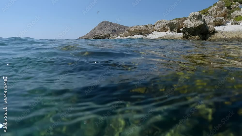 Underwater split level, coastal rocky landscape with rocky shore and underwater world, camera lowers underwater, Slow motion, Mediterranean Sea, Rhodes island, Greece Underwater split level, coastal rocky landscape with rocky shore and underwater world, camera lowers underwater, Slow motion, Mediterranean Sea, Rhodes island, Greece