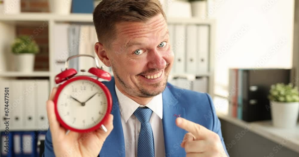 Portrait of smiling manager holding red alarm clock for ten in morning. Start of working day concept Portrait of smiling manager holding red alarm clock for ten in morning. Start of working day concept