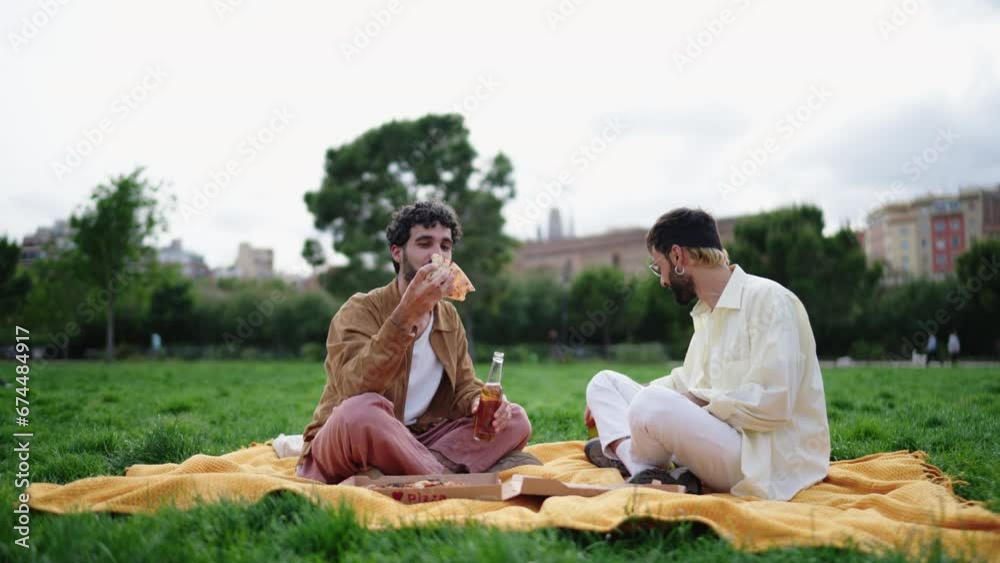 Two cheerful men share weekend picnic, enjoying beer and take away pizza in tranquil park setting, savoring each other's company. as two friends enjoy meal, their laughter mingling with beer toasting Two cheerful men share weekend picnic, enjoying beer and take away pizza in tranquil park setting, savoring each other's company. as two friends enjoy meal, their laughter mingling with beer toasting