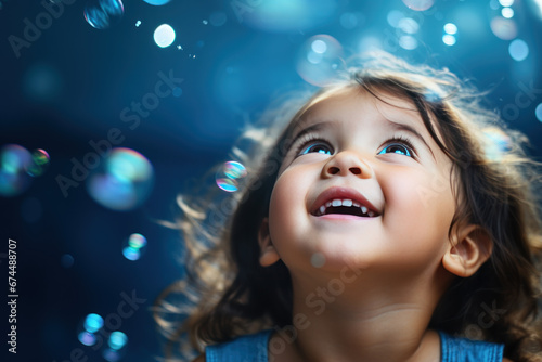 Happy brunette little girl excited looking up in the bubbles