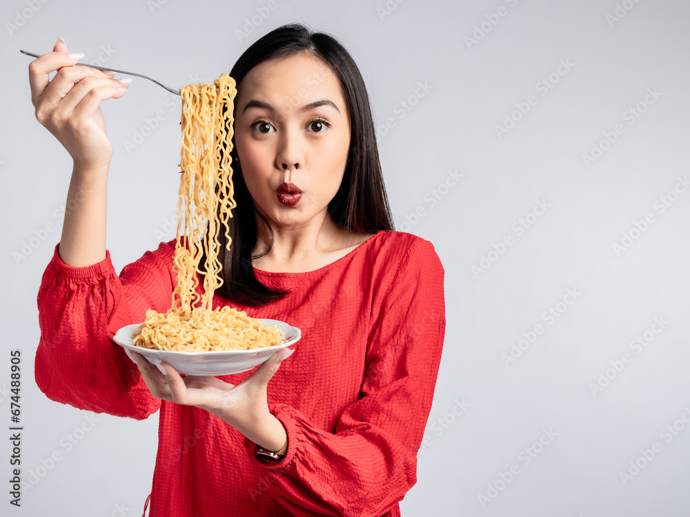 A portrait of a happy Asian woman wearing a red shirt, posing eating noodles. Isolated against a white background. A portrait of a happy Asian woman wearing a red shirt, posing eating noodles. Isolated against a white background.