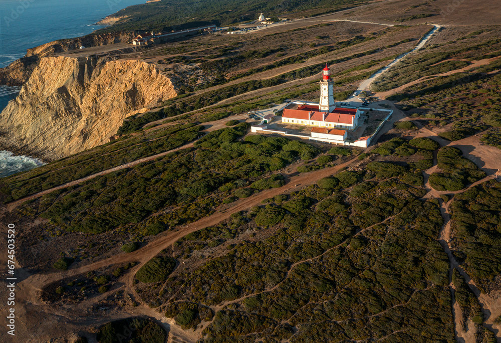 Lighthouse on high cliffs of cape Espichel, Portugal, at sunset