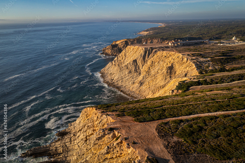 High cliffs of cape Espichel, Portugal and ocean tide at sunset