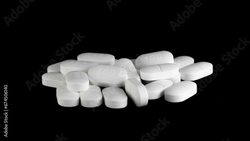 Pile of Sertraline 100mg pills on black background
