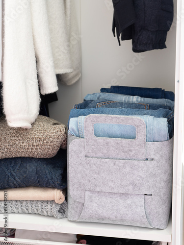 Felt baskets for storing things. Two felt boxes in the closet with neatly folded jeans and sweaters. Home storage system photo