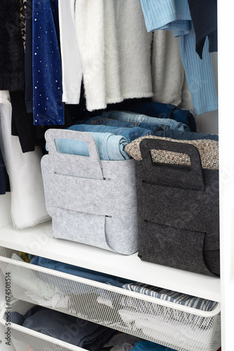 Felt baskets for storing things. Two felt boxes in the closet with neatly folded jeans and sweaters. Home storage system