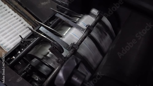 Working old printing machine printing newspaper in typographical printing house.