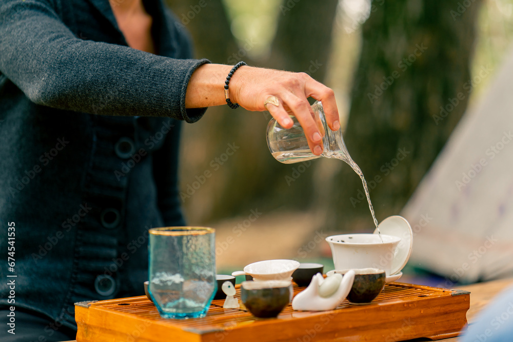A man's hand pours boiling water into ceramic bowls for making tea at tea ceremony masterclass