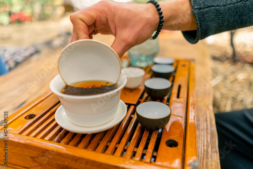 Close-up shot of natural Chinese tea leaves being brewed in a special ceramic bowl with lid during the ceremony