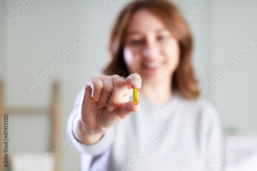 Woman holding yellow soft gel capsule
