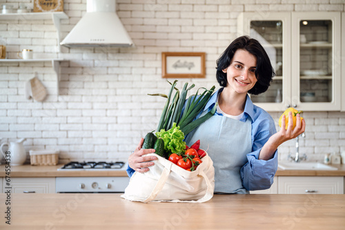 Smiling woman at home getting groceries out of shopping bag