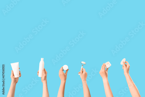 Female hands holding different cosmetic products on blue background