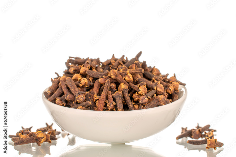 Dry aromatic cloves in a white ceramic bowl, macro, isolated on white background. Dry aromatic cloves in a white ceramic bowl, macro, isolated on white background.